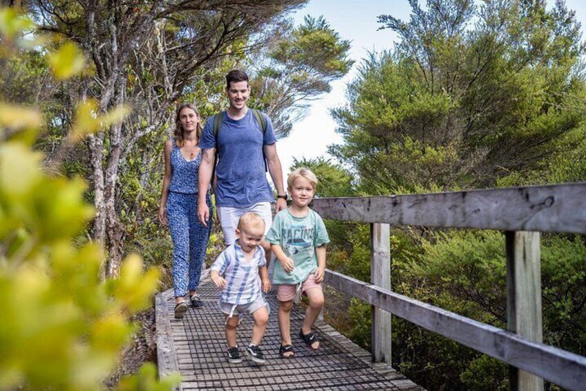A family walking on a wooden bridge surrounded by trees. 2