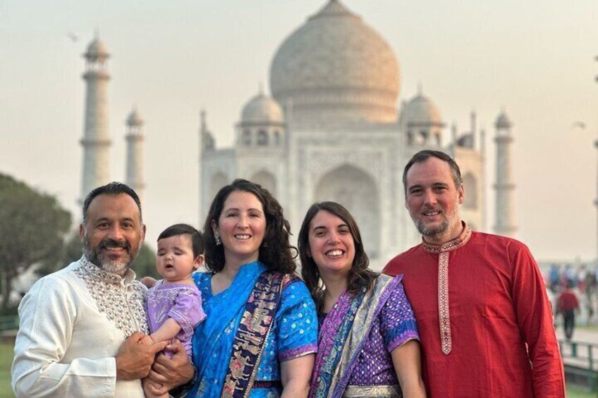 A family in traditional attire in front of the Taj Mahal. 1