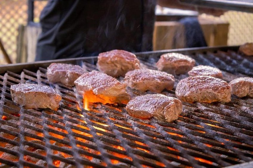 Meat being grilled on a barbecue with visible flames. 2