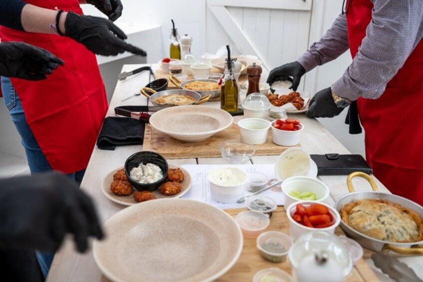 A person in a red apron preparing food at a table with various dishes and ingredients. 1