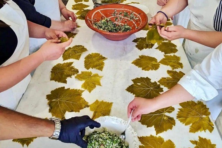 Persone sedute attorno a un tavolo con una ciotola di foglie verdi e un tovagliolo decorato con motivi vegetali. 2