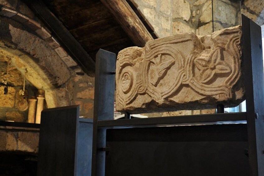 A carved stone with intricate designs, possibly a historical artifact, displayed in a museum or similar setting. 4