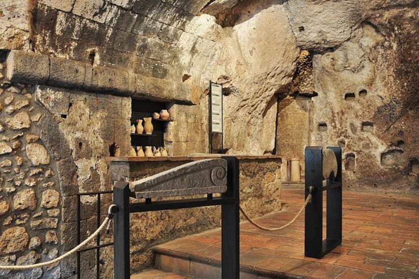 An ancient stone structure with a stone wall, a wooden door, and a metal gate. 2