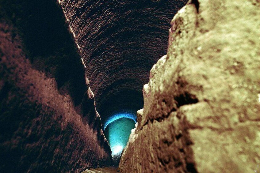 A narrow, rocky canyon with a blue light at the end. 3