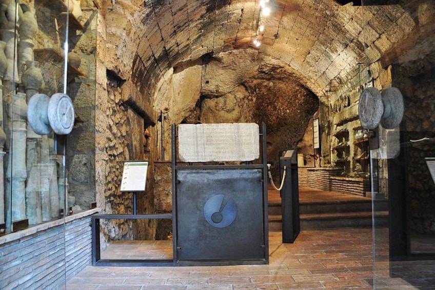 An underground stone structure with a metal door and informational signs. 5