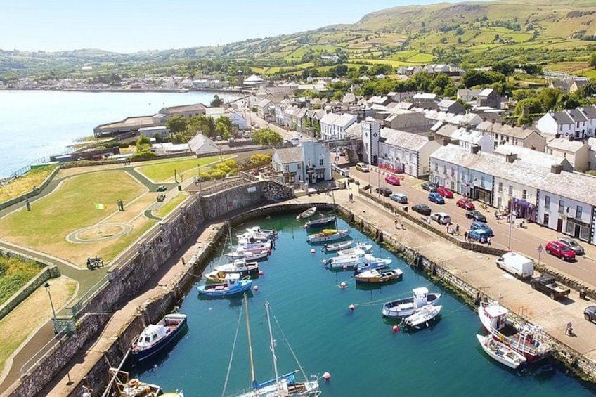 A harbor with boats docked, a stone wall, and buildings along the waterfront. 2