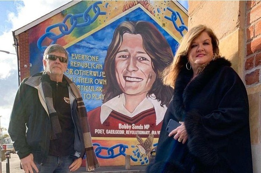 A mural with a person and text, a brick wall, and a clear sky. 4