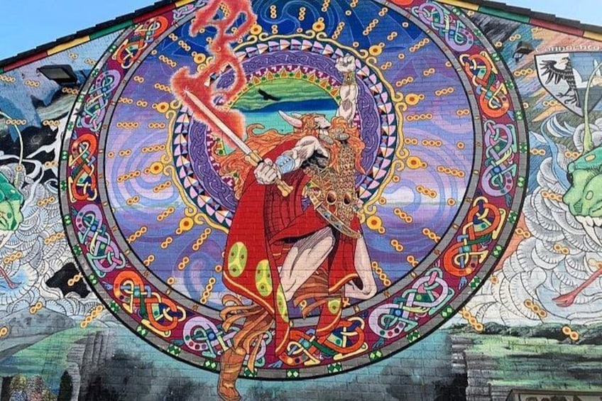 A colorful mural with a central figure holding a sword, surrounded by intricate designs and patterns. 5