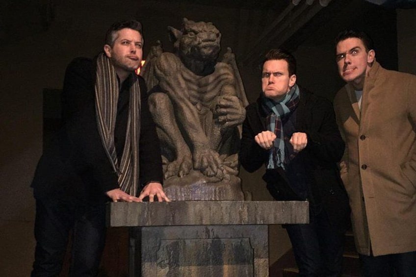Three people standing in front of a stone sculpture. 2