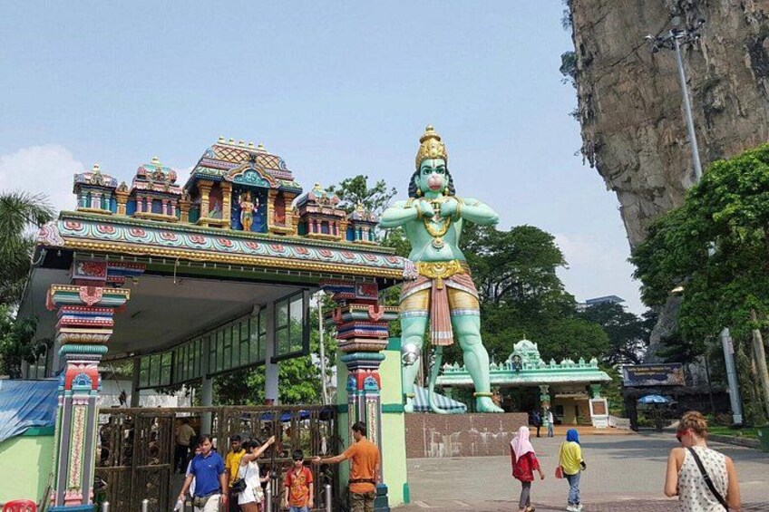 Una entrada a un templo con una estatua imponente, arquitectura colorida y un acantilado rocoso al fondo. 4
