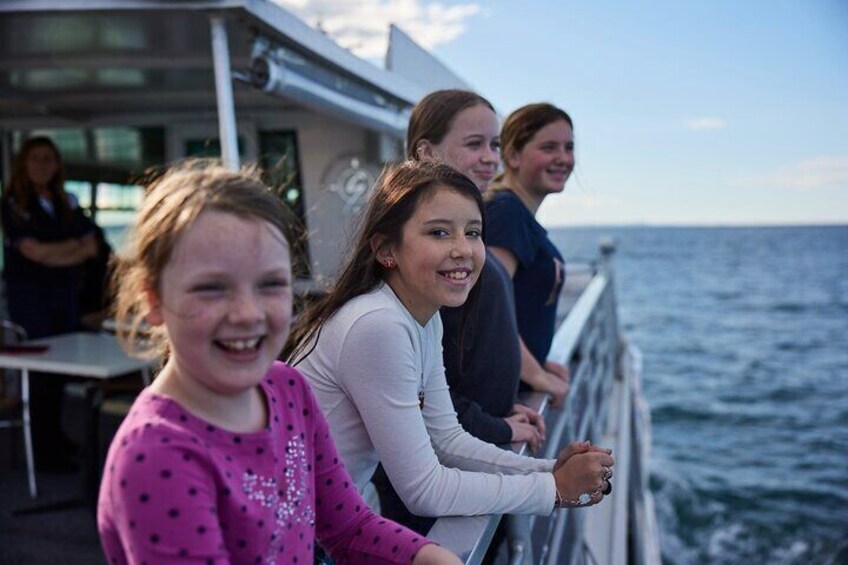 A group of people on a boat deck overlooking the ocean. 4