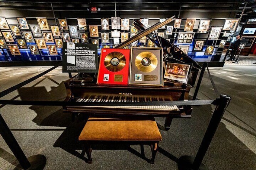 A grand piano with awards and a record on display. 2