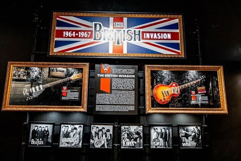 A display with guitars and framed pictures, including a sign about the British invasion of 1964-1967. 3
