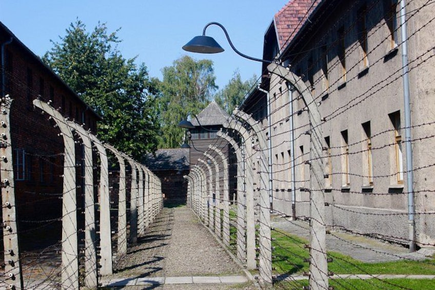 Eine historische Stätte mit einem langen Gang, der von Backsteingebäuden und Stacheldrahtzäunen gesäumt ist. 4