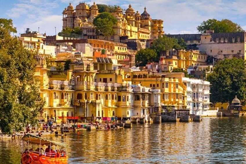 Un pueblo a orillas del río con edificios coloridos, una embarcación en el agua y una estructura en la cima de una colina. 1