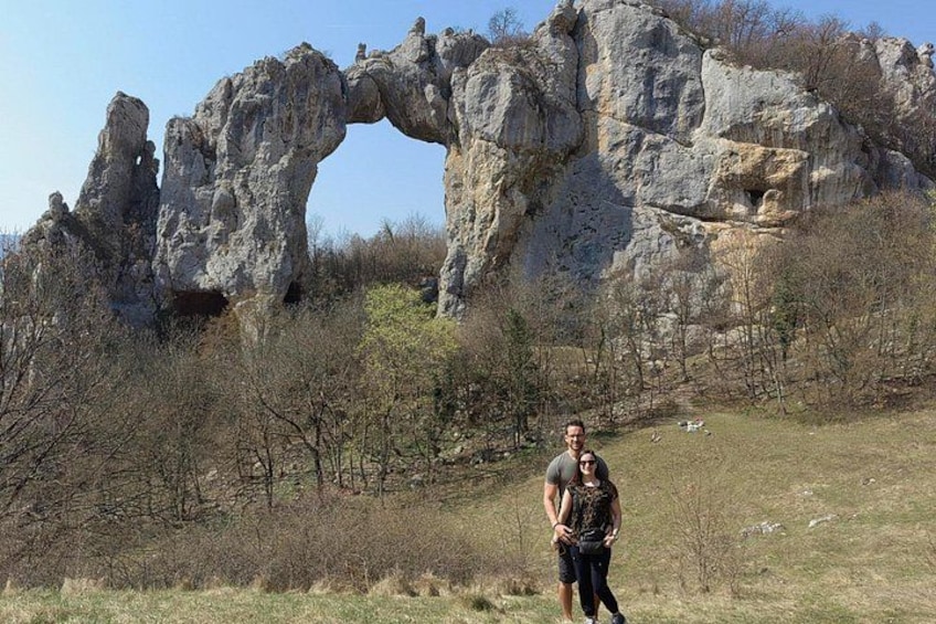 A person standing in a grassy field with a large rock formation in the background. 1