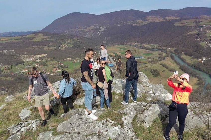 A group of people standing on rocky terrain with a valley and mountains in the background. 3