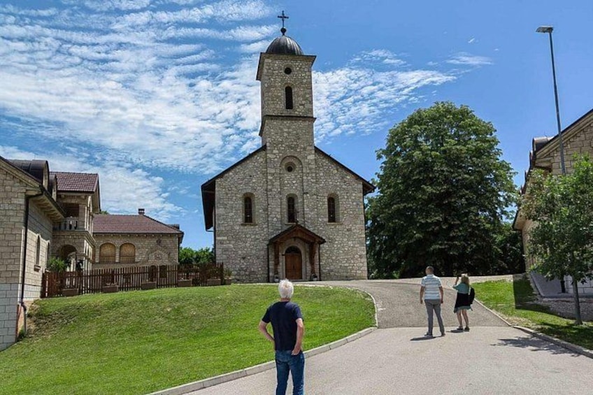 A church with a bell tower, a paved road, and a grassy area. 2