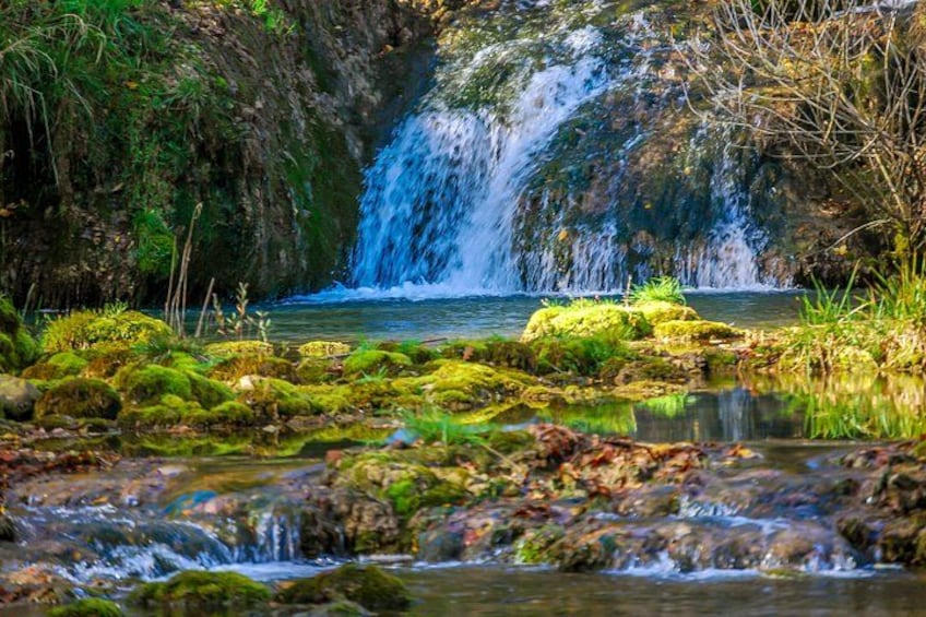 A waterfall, moss-covered rocks, and a calm stream. 4