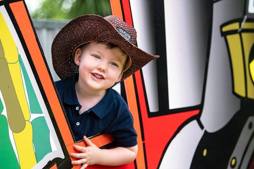A child in a straw hat leaning against a colorful mural. 2