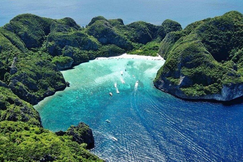 A coastal landscape with clear turquoise waters, lush green hills, and a sandy beach. 2