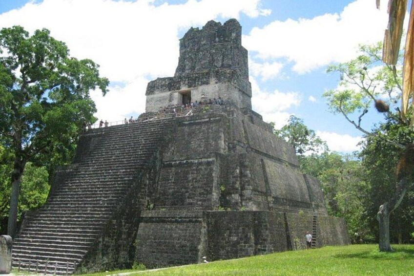 A large ancient pyramid with a staircase leading to the top, surrounded by lush greenery. 5