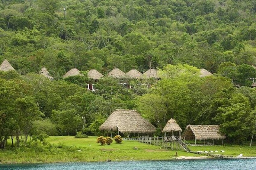 A coastal village with thatched-roof huts surrounded by lush greenery and a clear view of the sea. 2