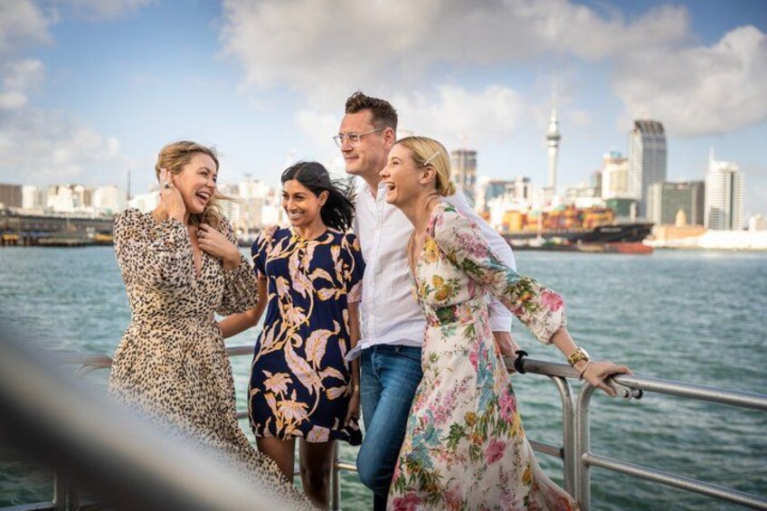 A group of people on a boat with a city skyline in the background. 1