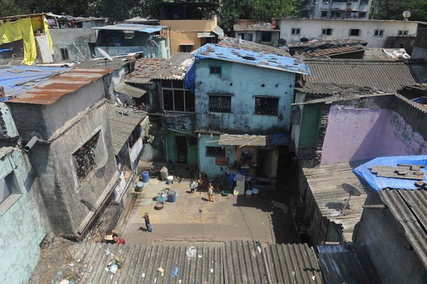 A densely packed urban area with multi-story buildings, some with corrugated metal roofs, and a central open space with scattered debris. 1