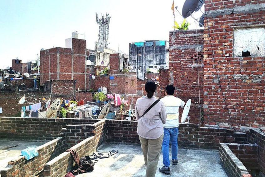A rooftop with two people, a brick building, and a satellite dish. 2