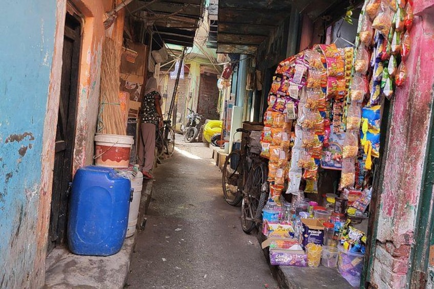 A narrow alleyway with a blue container, a bicycle, and a shop selling snacks. 3