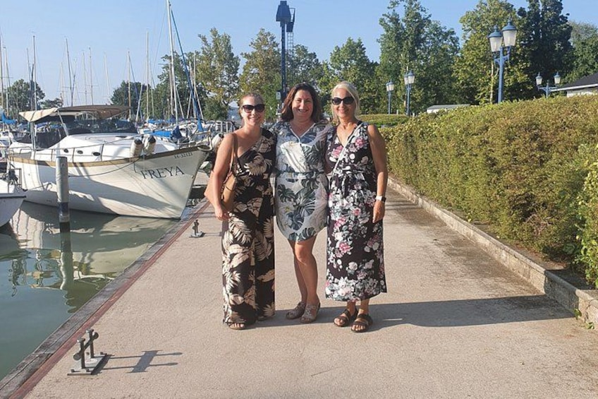 Three people standing on a dock with boats in the background. 3