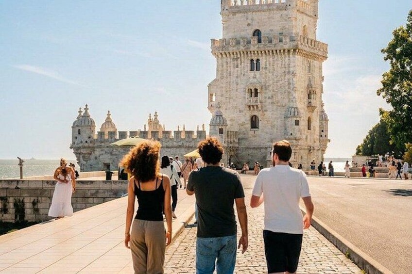 A historic tower, a waterfront, and people walking along a promenade. 5