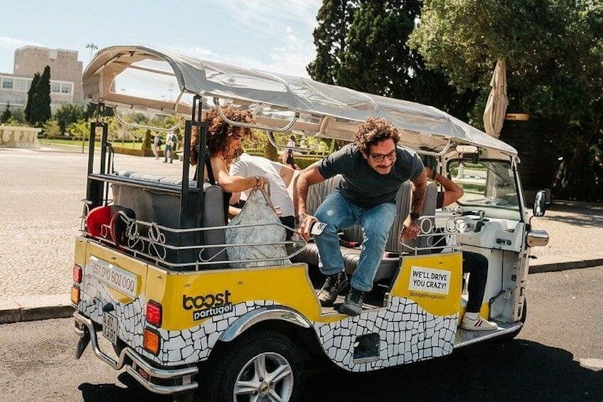 A yellow and white vehicle with a mosaic pattern, labeled 'boost Portugal,' parked on a street. 2