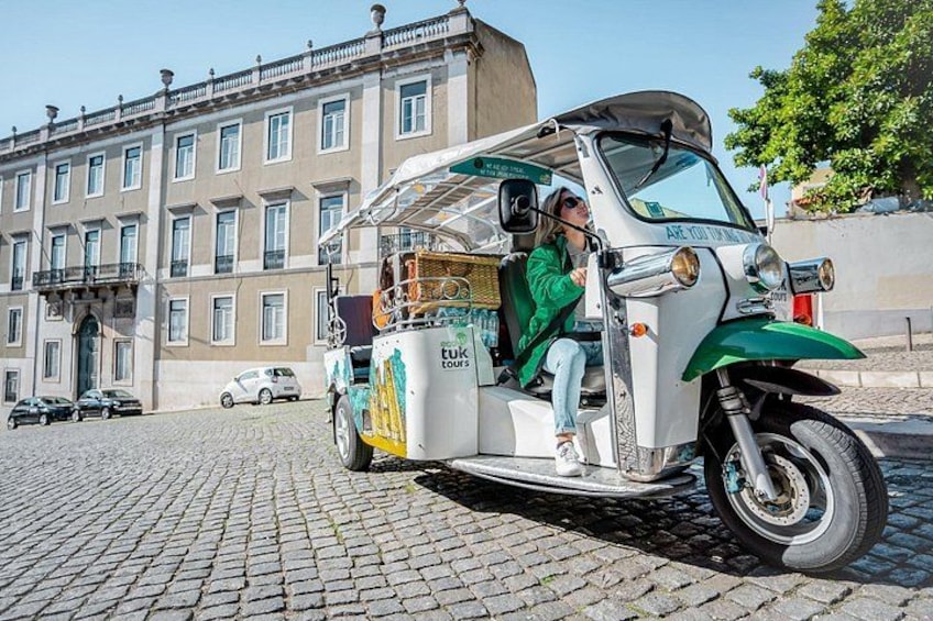 En tuk-tuk står parkerad på en kullerstensgata med en byggnad i bakgrunden. 2