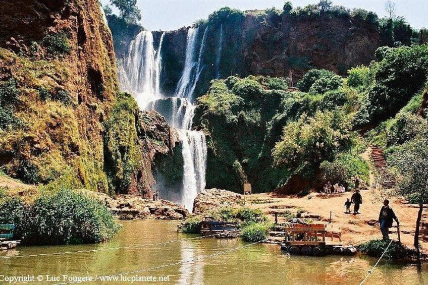 A waterfall, a river, and people near the water. 2