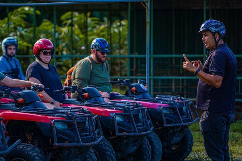 A group of people on ATVs, a red ATV, and a green structure in the background. 5