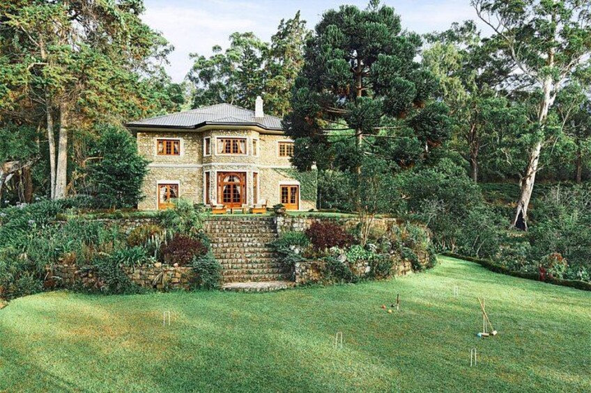 A stone house with a well-manicured lawn and a stone staircase leading to the entrance. 1