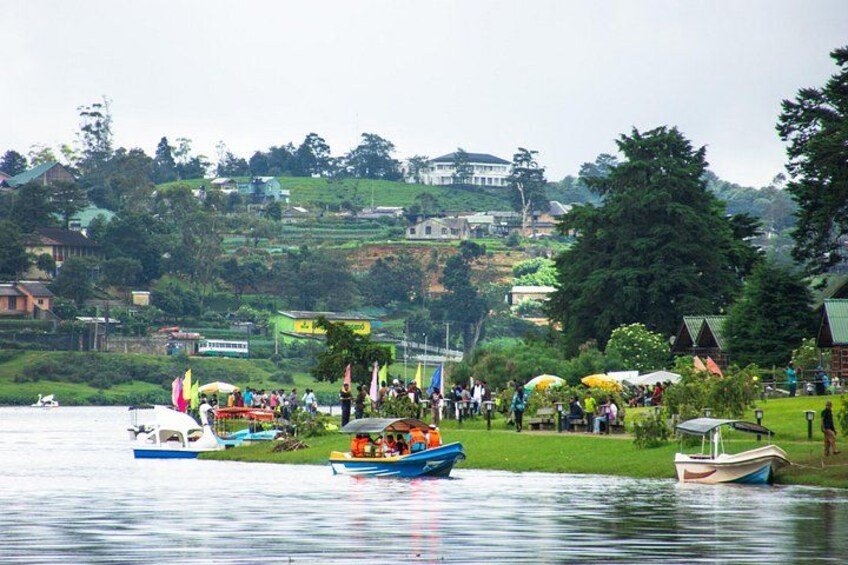 A lake with boats, people, and a hillside with buildings. 3