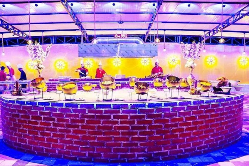 A circular brick structure with a stage, surrounded by tables and chairs, and a group of people in the background. 3