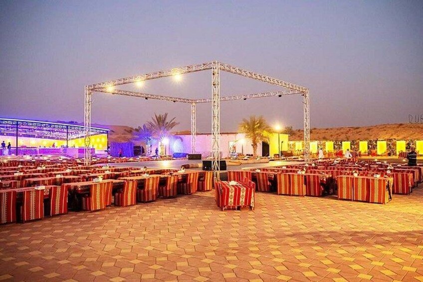 An outdoor event with a stage, seating, and palm trees. 5