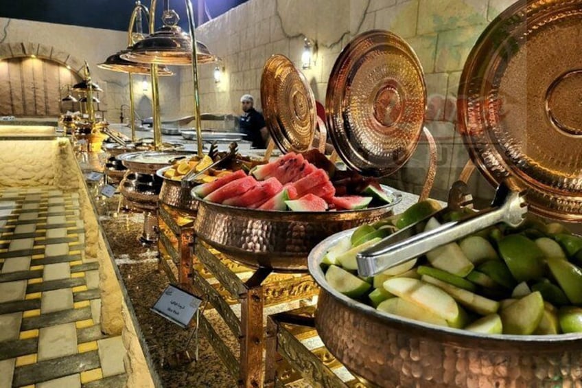 A buffet with various food items, including fruits and vegetables, in a well-lit indoor setting. 4