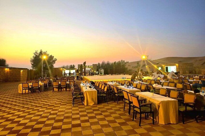 An outdoor dining area with checkered flooring, tables with yellow tablecloths, and a sunset in the background. 3