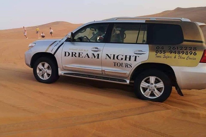 Un SUV blanco con la leyenda 'DREAM NIGHT TOURS' estacionado en el desierto. 3