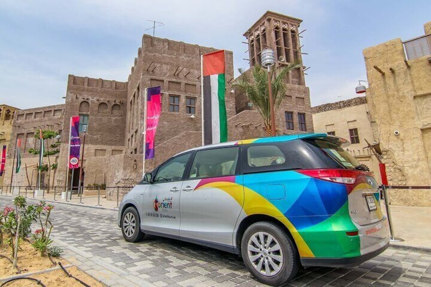 A colorful car parked in front of a historic building with a tall tower. 4