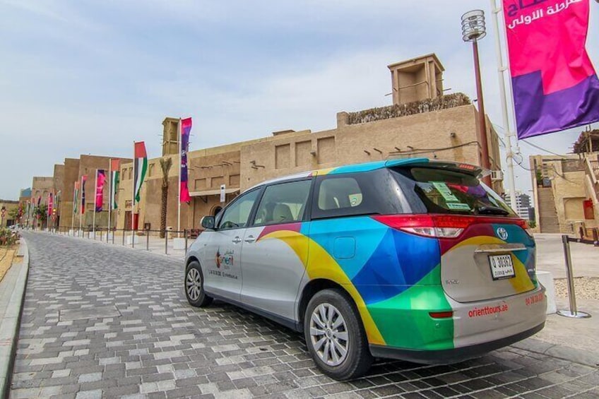 A colorful car parked on a paved street with flags and buildings in the background. 3