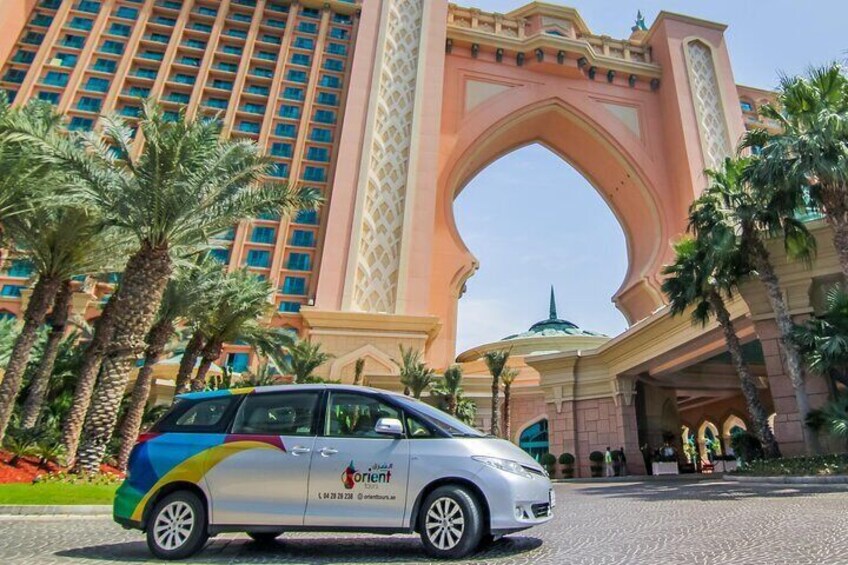 A silver car with a colorful design parked in front of a large, ornate building with a distinctive archway. 1