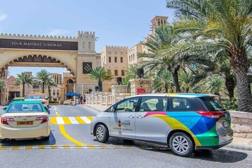 A car with a colorful design parked in front of a gate labeled 'SOUK MADINAT JUMEIRAH.' 2