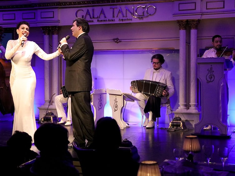 A stage with a singer, a man in a suit, and a musician playing a wind instrument. 3