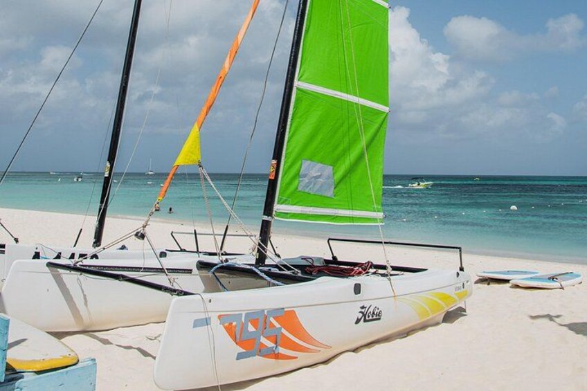 A sailboat with a green sail on a sandy beach. 2